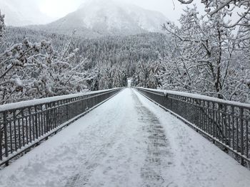 Snow covered footbridge against sky