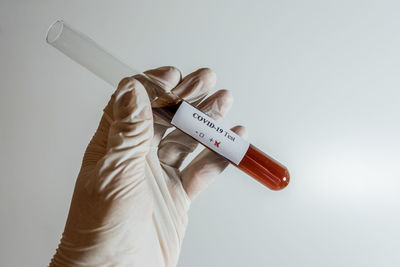 Close-up of hand holding bottle against white background