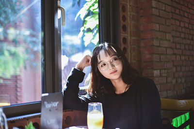 Young woman sitting at table by window in cafe