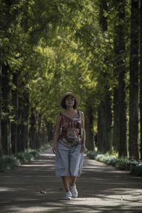 Full length of woman standing on footpath against trees