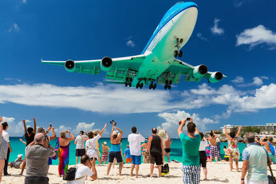 People at airplane against sky