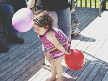 High angle view of girl playing with balloon while standing by mother outdoors