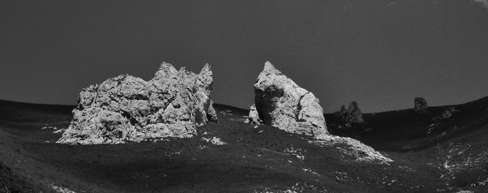 Rock formations in sea against clear sky