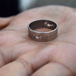 Cropped image of hand holding love text ring