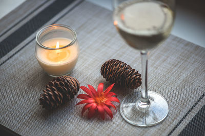 High angle view of pine cones and candle with wine on fabric