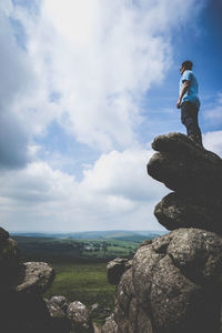 Low angle view of man standing on cliff against sky