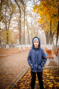 Portrait of young woman standing on road during autumn