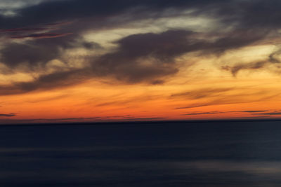 Scenic view of sea against dramatic sky during sunset