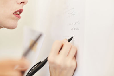 Cropped image of businesswoman writing on whiteboard in office