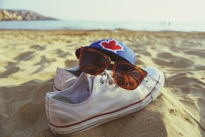 Sunglass and shoes with cap at sandy beach