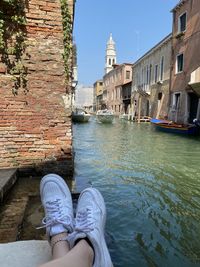 Low section of person on canal against buildings