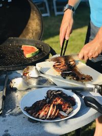 Low section of man preparing food on barbecue grill outdoor