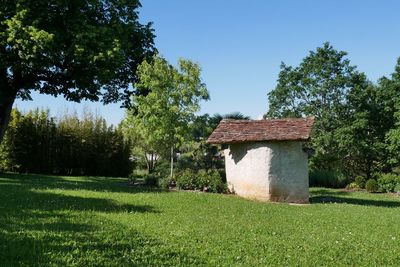 Built structure on field by trees against sky