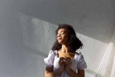 Portrait of young woman standing against wall