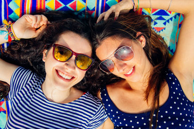 High angle view of friends wearing sunglasses while lying on blanket at beach