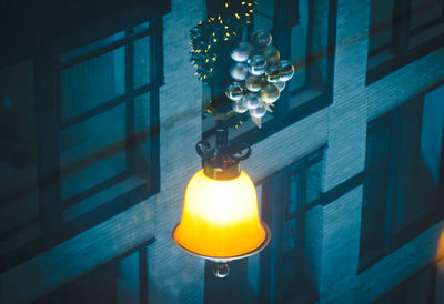 Close-up of illuminated light bulb hanging from ceiling