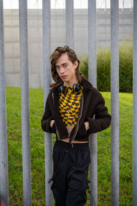 Portrait of young woman standing against fence