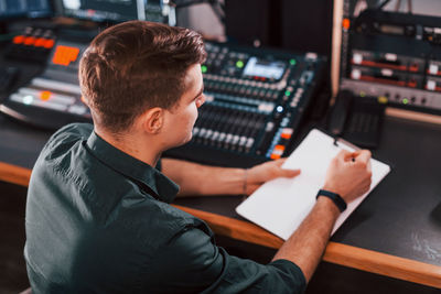 Document with scenario. young man is indoors in the radio studio is busy by broadcast.