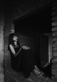 Portrait of young woman sitting in abandoned building