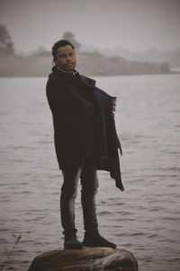 Rear view of man standing by lake in winter