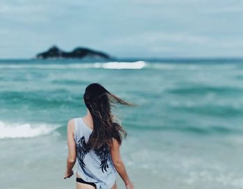 Rear view of woman standing at beach