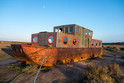 Abandoned boat moored on beach against clear sky