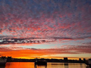 Silhouette buildings against dramatic sky during sunset