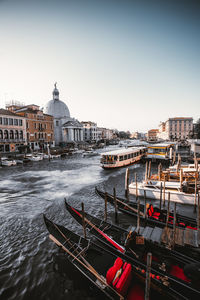 Boats moored in canal by buildings against sky in city