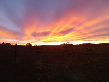 Scenic view of dramatic sky over land during sunset