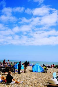 People on beach against cloudy sky