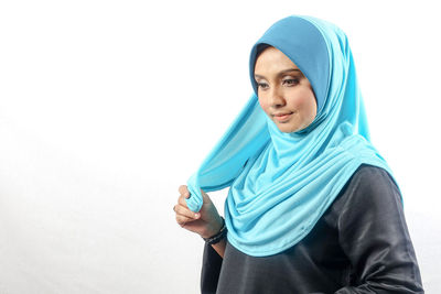 Smiling woman wearing hijab against white background