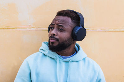 Portrait of young man looking away against wall