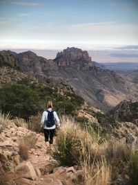 Rear view of man walking on mountain against sky