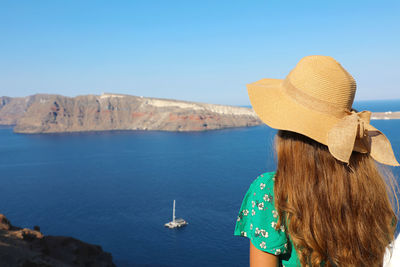 Rear view of woman looking at sea against clear blue sky