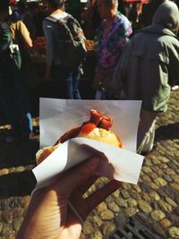 Cropped hand of woman holding burger in city