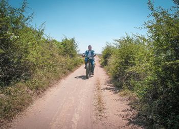 Rear view of man riding bicycle on road