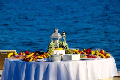 Various fruits on table with lamp against blue water