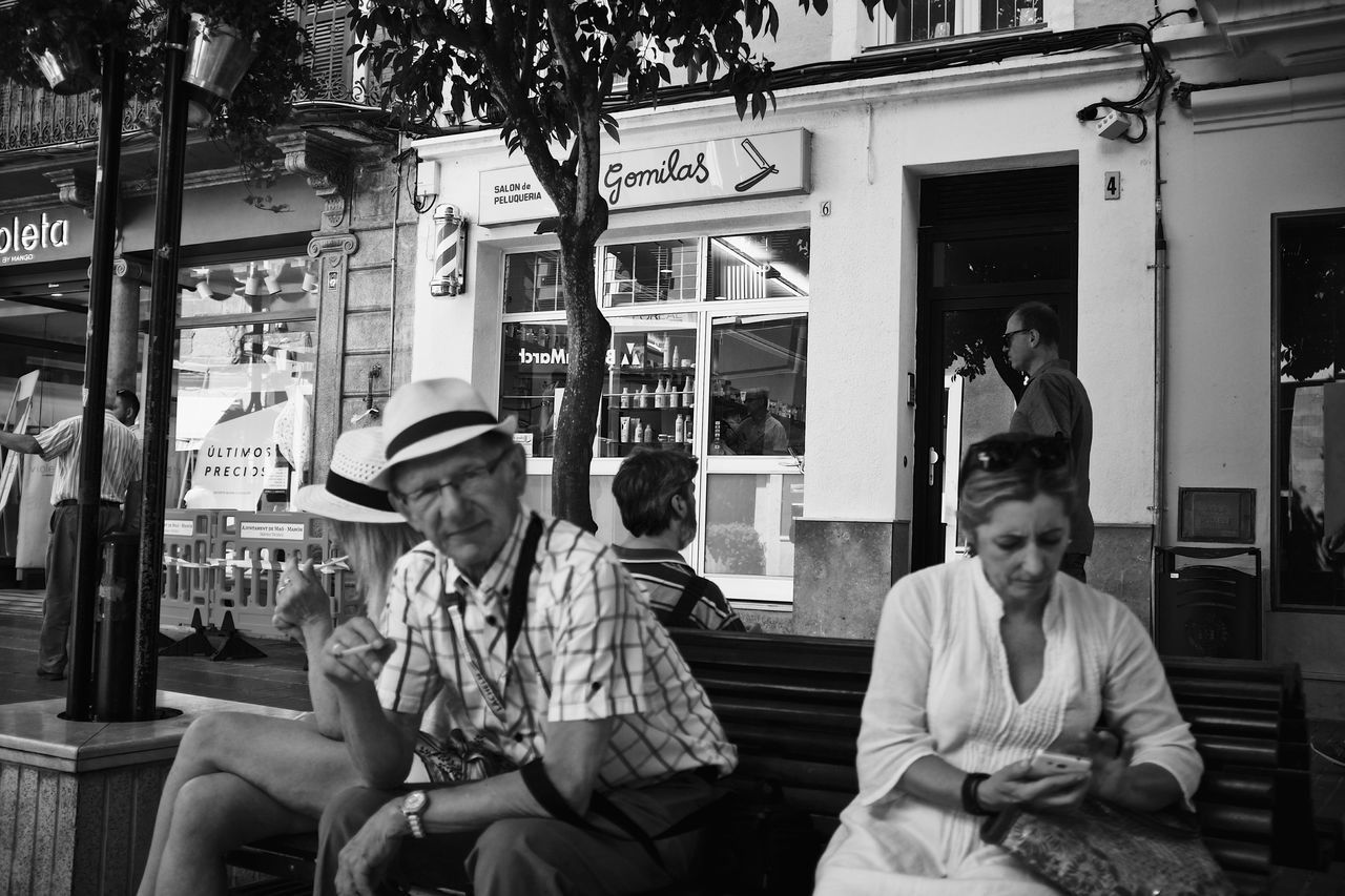 sitting, real people, building exterior, transportation, casual clothing, day, architecture, public transportation, city, lifestyles, land vehicle, outdoors, built structure, men, young adult, people