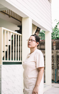 Portrait of young woman standing against building