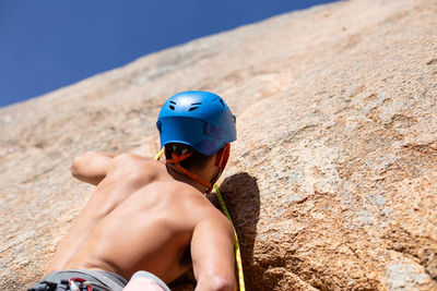 Rear view of shirtless man climbing rock