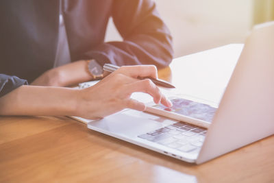 Midsection of woman using mobile phone while sitting on table