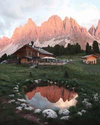 Built structure by lake and mountains against sky