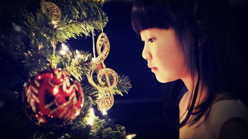 Close-up of cute girl looking at illuminated christmas tree