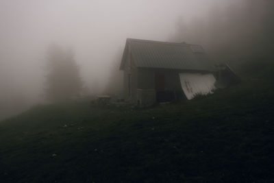 House on field by trees against sky