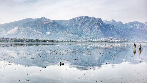 Scenic view of lake by snowcapped mountains against sky