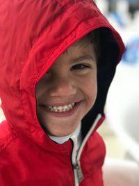 Close-up portrait of cute smiling boy wearing red hooded shirt