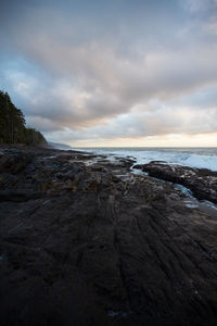 Black rock leading into wild ocean on rugged pacific coast on an autumn sunset