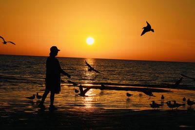 Silhouette man with arms outstretched standing at sunset