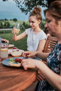 Family having a meal from grill during summer picnic outdoor dinner in a home garden