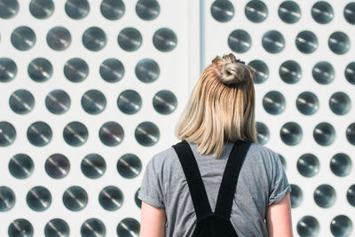 Rear view of woman standing by patterned wall